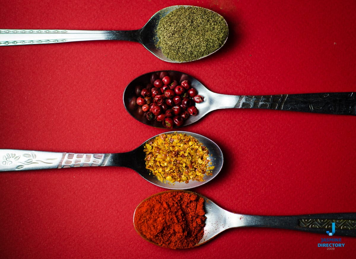 Different spices in spoons and red background