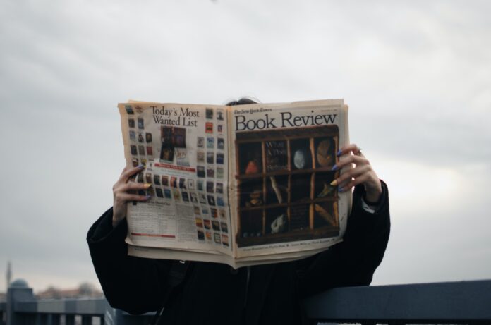 Person Holding White and Brown Newspaper