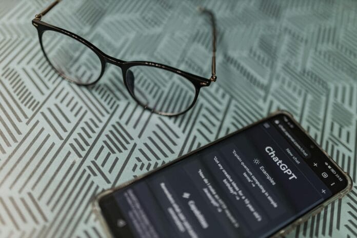 A smart phone with glasses on it next to a book