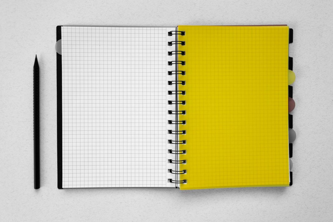 Flat lay of a spiral notebook with graphing paper and a pencil on a neutral background.