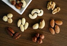 Close-up of various nuts on a wooden table, showcasing healthy snacking options.