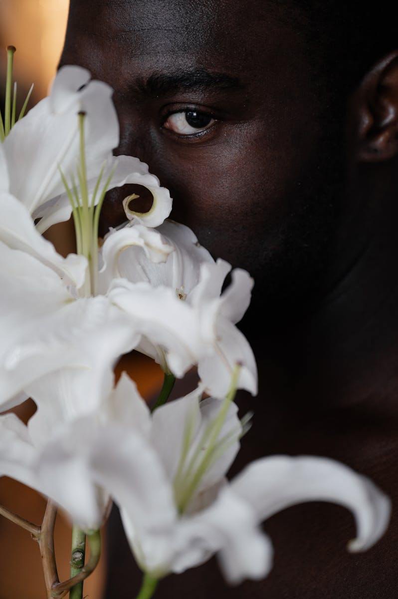 A captivating portrait of a man partially hidden behind a delicate bouquet of white lilies.