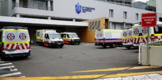 2026: Best physician directories serving Australia Ambulances parked at a hospital emergency entrance with checkerboard livery, representing healthcare infrastructure and medical service accessibility in Australia.