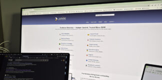 How UK solicitors win clients through directories Two computer screens displaying a business directory website in a dark office, illustrating how solicitors use online directories to connect with potential clients.