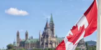 Canadian flag waves in front of Parliament Hill's Peace Tower in Ottawa, representing the national legal framework underpinning Canadian law firm directories.