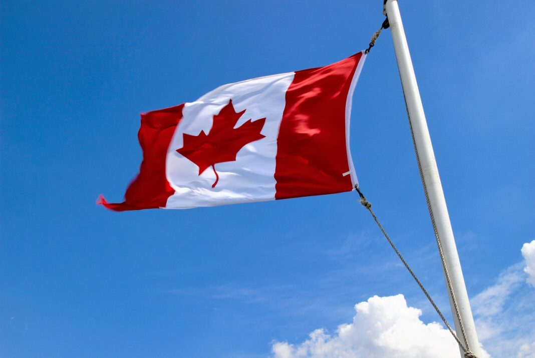 Canadian flag symbolizes national identity for law firms seeking directory listings Canadian flag with red maple leaf waving on flagpole against blue sky, representing Canadian law firm identity for professional directory registration.