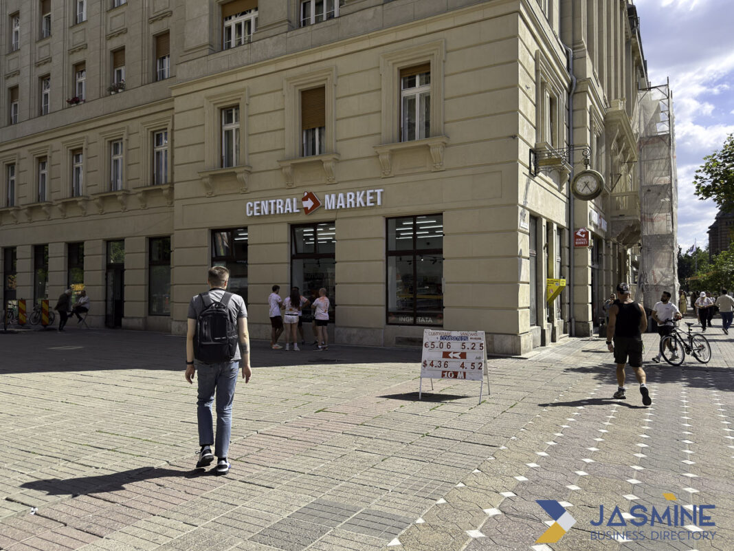 Traditional market storefront illustrates physical business directory concept versus online marketplace platforms Street corner view of Central Market storefront with pedestrians on plaza, illustrating the physical business directory model compared to digital marketplace platforms.
