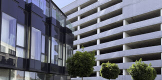 Smart Funding Strategies Every Growing Small Business Should Know Modern office building with glass facade next to concrete parking structure with landscaped courtyard, illustrating professional infrastructure for legal directory services.