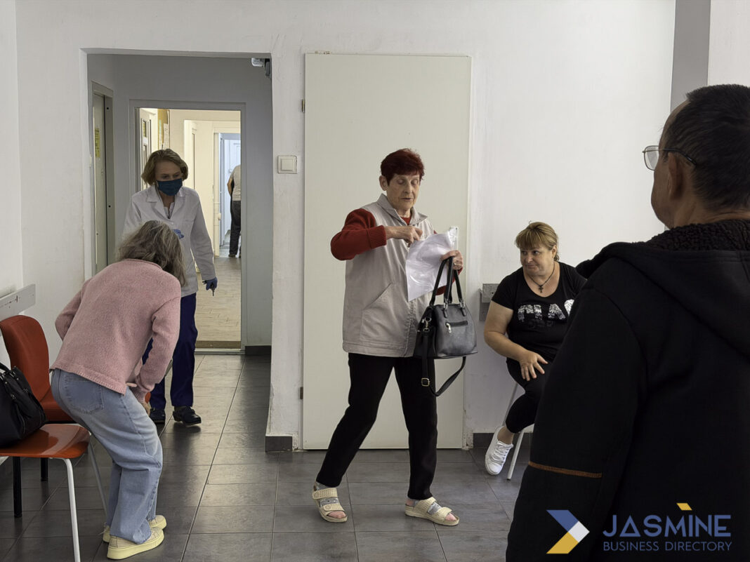 Medical professional in clinical setting illustrating physician directory and healthcare facility environment. Healthcare professional in white coat holds papers in medical facility waiting room, representing physician directory listings and clinical practice environments.