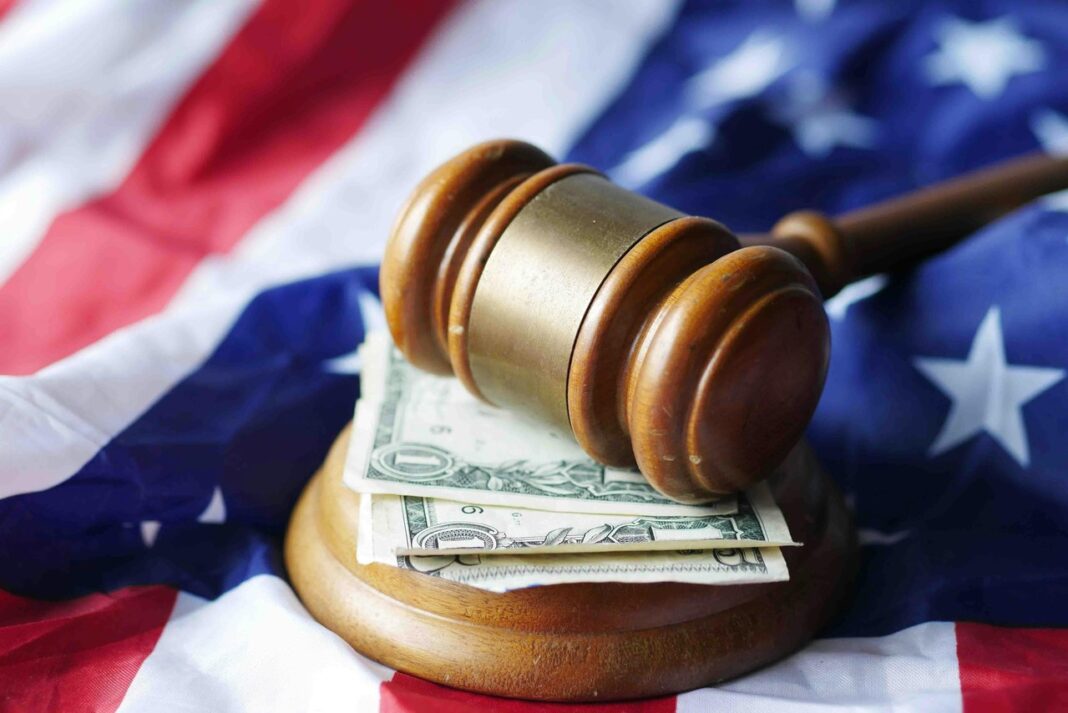Judicial gavel on currency symbolizes legal authority and costs central to law firm directory visibility Wooden judicial gavel with gold band rests on dollar bills and American flag, representing the legal authority and financial aspects of law firm services.