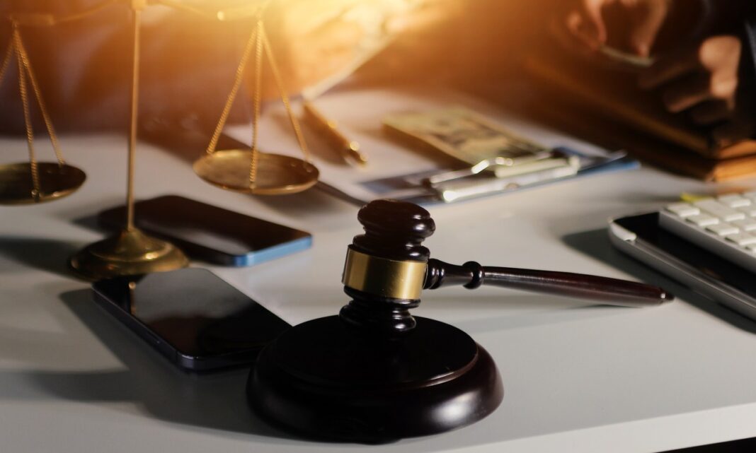 Legal office tools symbolizing the decision-making process Canadian lawyers use when selecting professional directories Wooden gavel and brass balance scale on office desk with papers and calculator, representing the careful evaluation lawyers undertake when choosing professional directories.