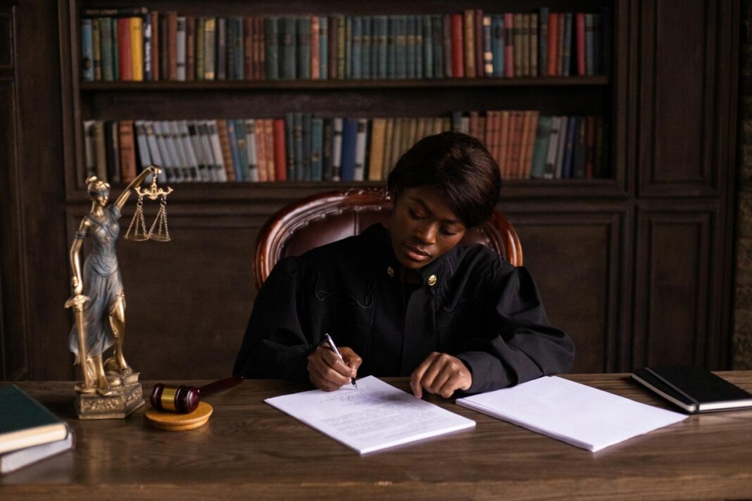 Legal professional reviewing documents illustrates how Australian solicitors research and evaluate legal directories Legal professional in judicial robes writing at desk with gavel and law books, representing the deliberative process solicitors use when choosing legal directories.