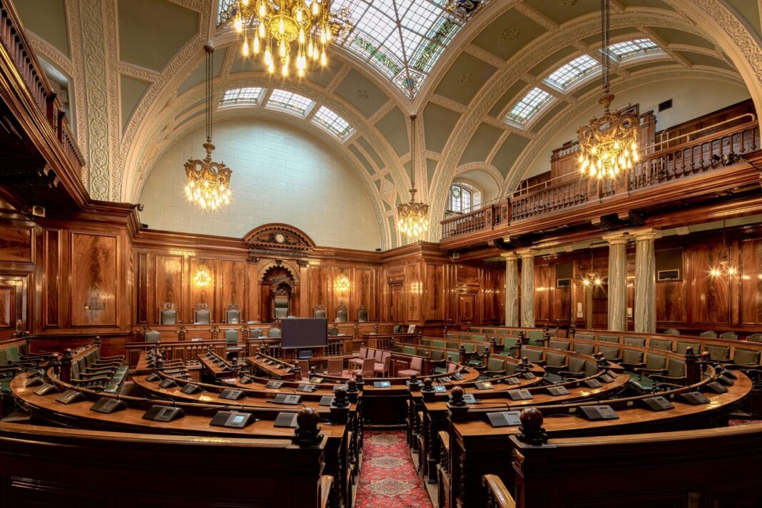 Legislative chamber interior exemplifying the institutional architecture featured in government directories Ornate legislative chamber with tiered semicircular seating, chandeliers, and wood paneling, representing government institutional spaces included in official directories.