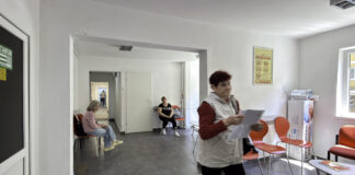 A 2026 guide to physician directory listings in the US A medical clinic waiting room with orange chairs and motion-blurred patient holding paperwork, representing healthcare accessibility and physician directory navigation.
