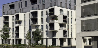 How real estate firms use online directories in 2026 Modern apartment building with white balconies and commercial ground floor in Timișoara, representing the type of property featured in real estate online directories.
