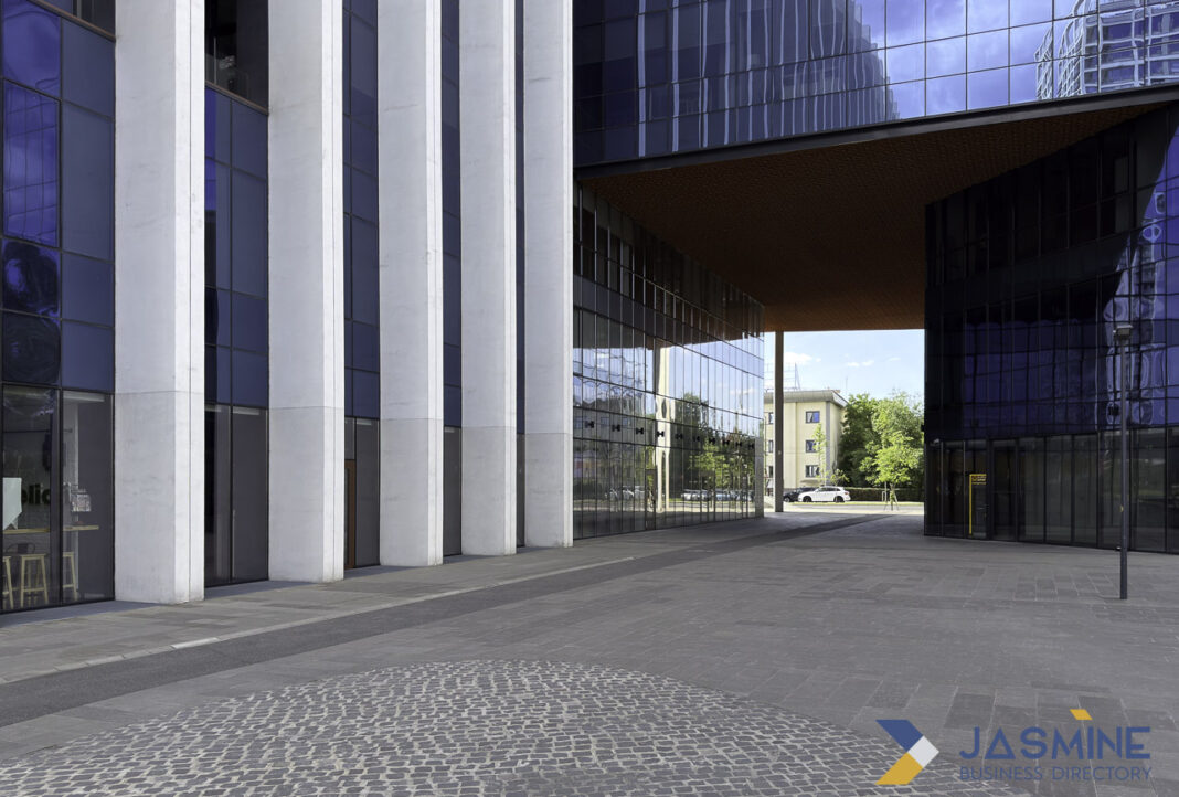 Contemporary office architecture represents the modern professional infrastructure supporting Florida's legal directory A modern glass office building with covered passageway and cobblestone plaza, illustrating the contemporary professional infrastructure of law firm environments.