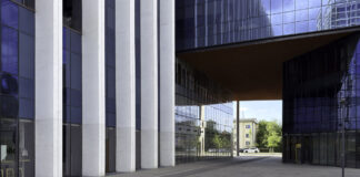 Florida law firm directories: a closer look A modern glass office building with covered passageway and cobblestone plaza, illustrating the contemporary professional infrastructure of law firm environments.