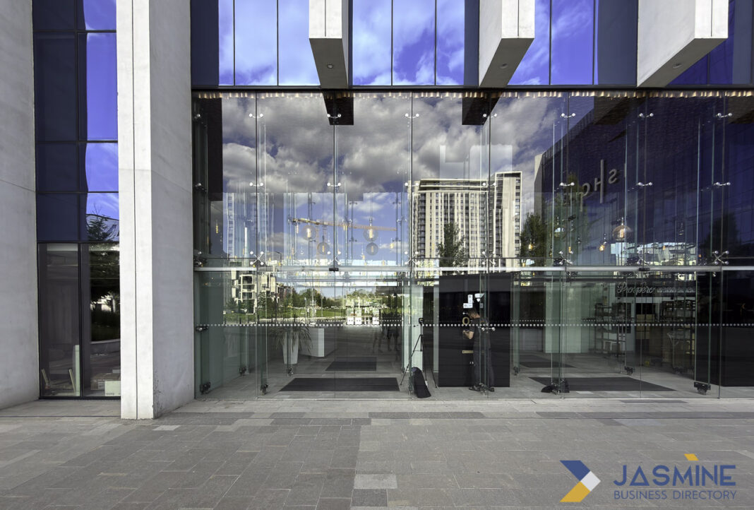Polished commercial entrance exemplifies how one strong business presence outperforms multiple weak listings Modern glass commercial building entrance with reflective facade and LED lighting, illustrating a single high-quality business presence that stands out through professional presentation.
