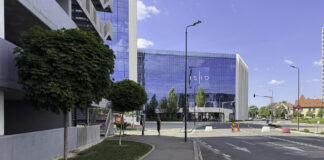 Why accurate business listings matter in 2026 Modern blue glass business center with clear signage in an urban plaza, illustrating the importance of visible and accessible business locations for customer discovery.
