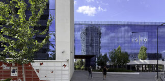 Contemporary glass-facade business center with delivery lockers in an urban plaza, representing the modern commercial infrastructure that enhances business visibility and customer access.