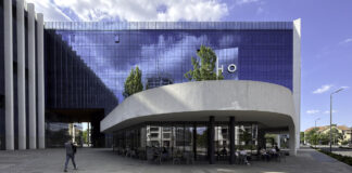How the product life cycle shapes critical decisions for growing brands Contemporary glass office building with curved white canopy and outdoor cafe plaza in Timișoara, illustrating the commercial infrastructure where businesses maintain directory listings.