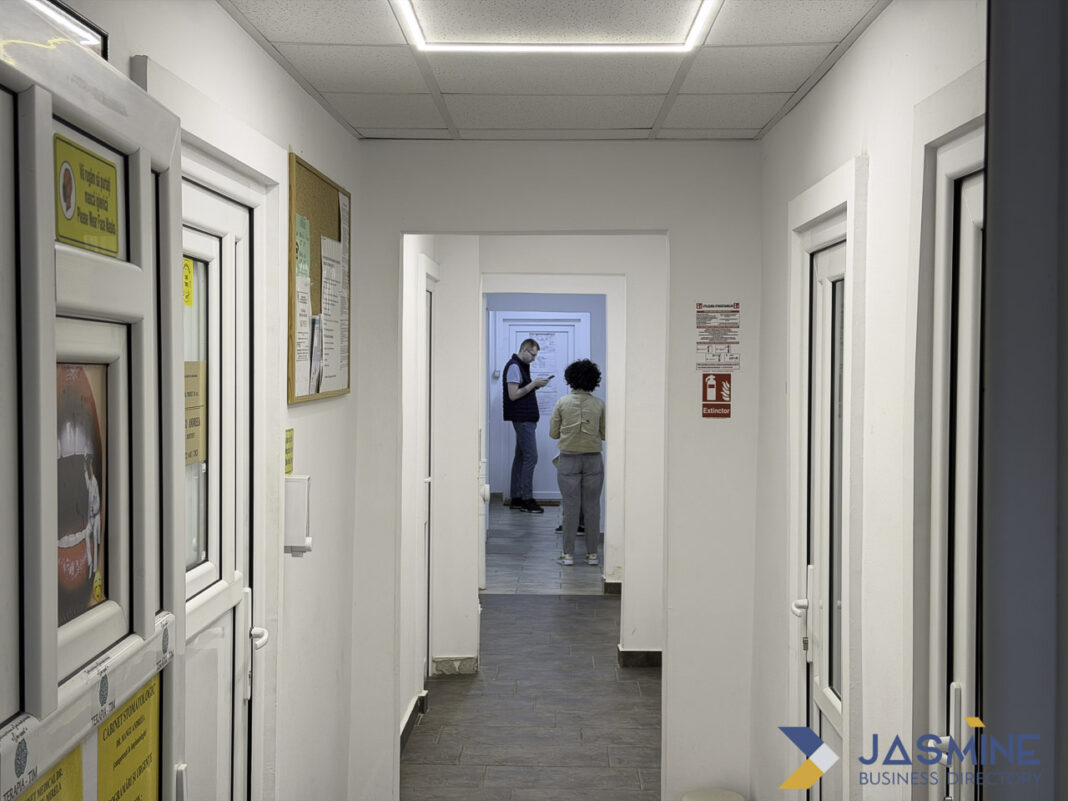 Professional office corridor interior illustrating law firm workspace infrastructure Modern office corridor with white walls and multiple doorways showing two people in the background, representing the professional workspace infrastructure of law firms.