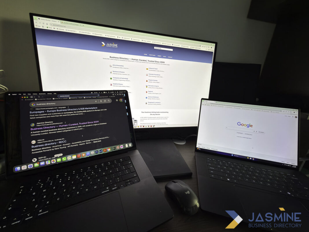Multi-device workspace displaying business directory interfaces for creating effective online listings Three-screen workspace with laptops and monitor displaying business directory pages, illustrating the digital tools used to create and manage online business listings.