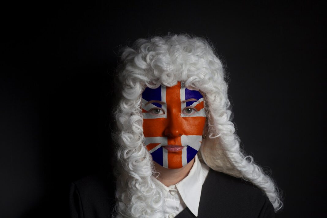 Traditional British legal imagery meets contemporary digital practice in UK barristers' professional directories Person wearing white curled period wig and Union Jack face paint in studio portrait, representing British legal tradition for article about barristers using online directories.