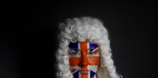 How UK barristers use online legal directories Person wearing white curled period wig and Union Jack face paint in studio portrait, representing British legal tradition for article about barristers using online directories.