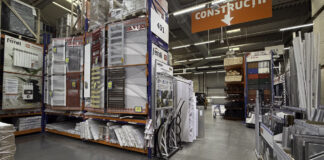 The elements of a complete business listing Warehouse store interior with organized shelving displaying construction products and directional signage, illustrating the physical infrastructure that supports complete business listing information.