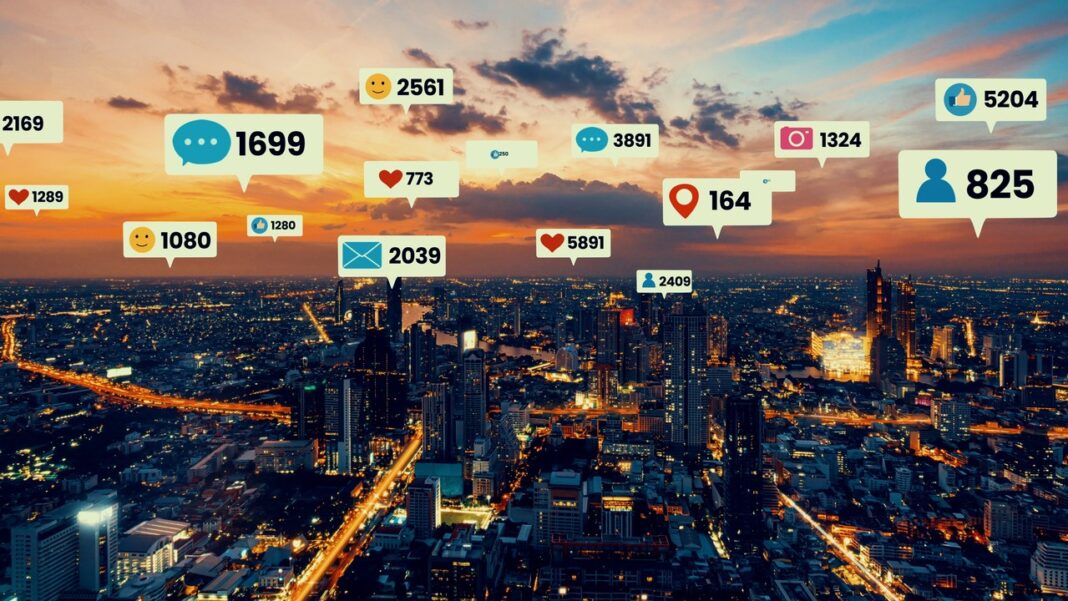 Social Media Engagement Metrics Visualized Over City Landscape for Local Digital Marketing Strategy Aerial view of an illuminated cityscape at dusk with overlaid social media engagement metrics in white speech bubbles, illustrating digital reach and local social media visibility.