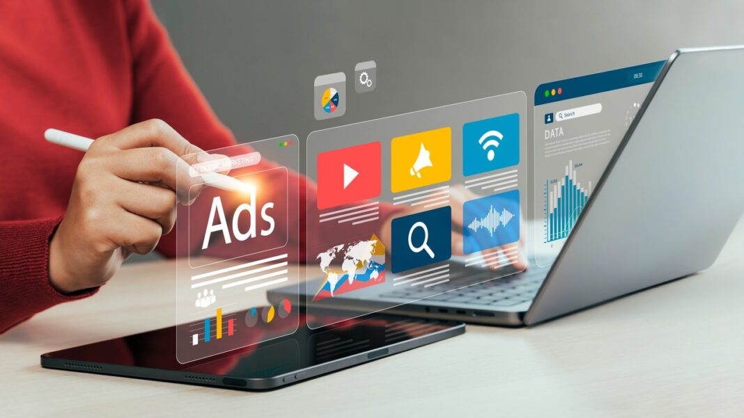 Creating optimized content for AI discovery through digital marketing platforms Person working on tablet with stylus while laptop sits nearby, holographic advertising and analytics icons floating above the workspace, illustrating content creation for AI-driven directory platforms.