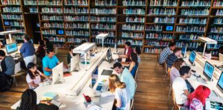 The skills intelligence professionals need to succeed Students work at white desks with laptops in a library surrounded by bookshelves, representing the research process involved in finding effective keywords.