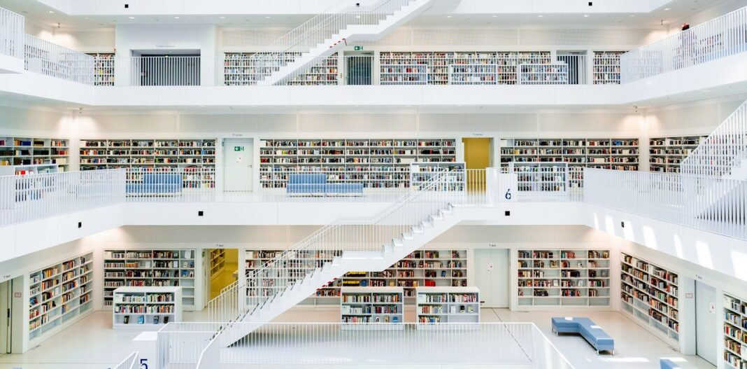Modern library's hierarchical architecture illustrates systematic site structure and navigation principles A multi-story modern library with organized bookshelves on multiple levels connected by white staircases, illustrating hierarchical structure and systematic organization for site navigation.