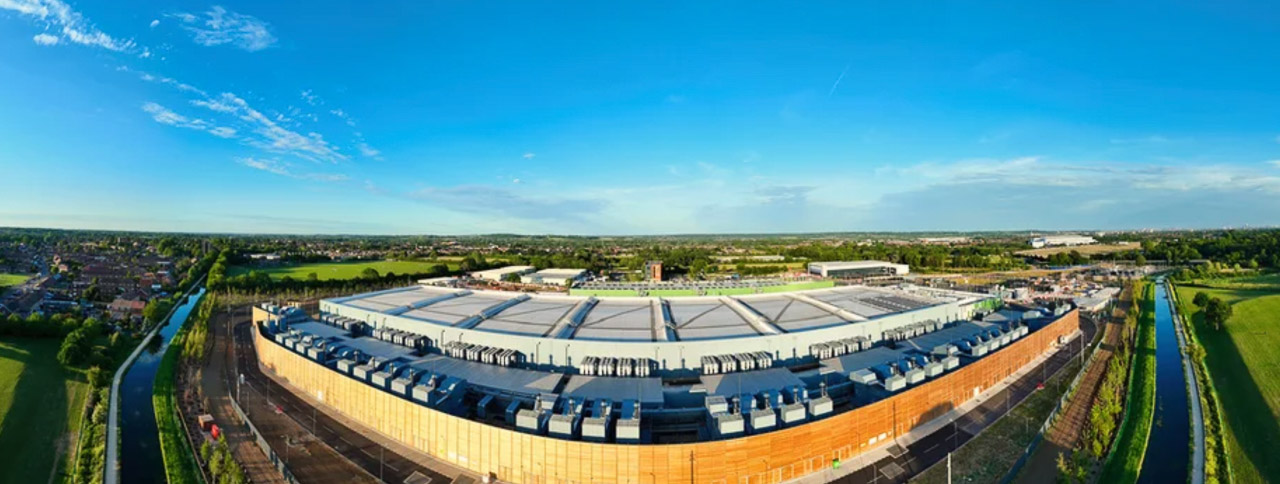 Aerial view of a modern warehouse complex with curved metallic roof and loading bays, representing the infrastructure that supports local business distribution and operations.