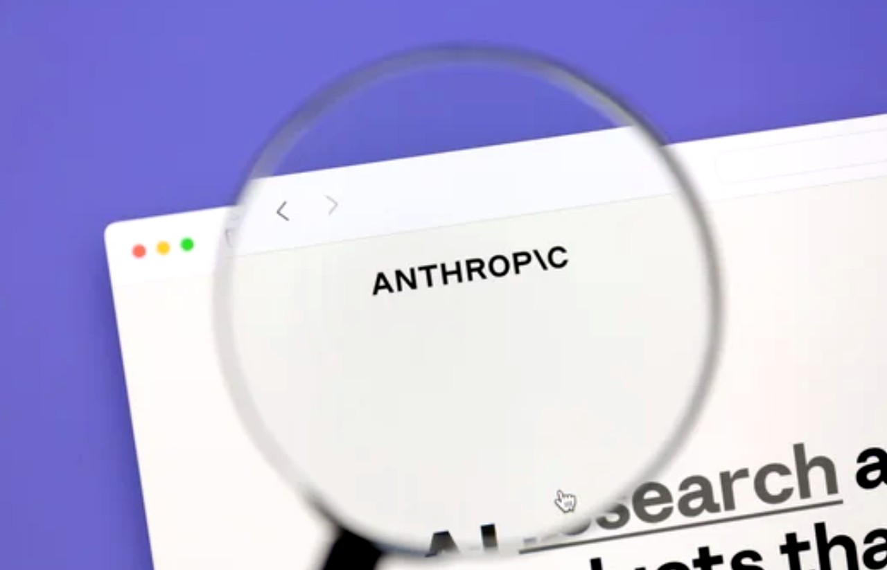 Magnifying glass examining a browser window displaying Anthropic branding, representing scrutiny of AI marketing tools and platforms that automate content production.