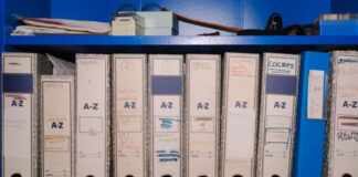 What Sets Curated Directories Apart in AI Citation White archival binders with handwritten A-Z labels line a blue shelf, demonstrating the systematic organization principles that distinguish curated directories.