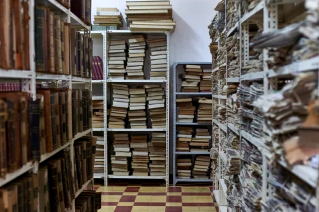 Organized archive storage illustrates categorization principles in directory structures Dense archive storage room with metal shelves packed with bound volumes and checkered tile floor, illustrating systematic organization and categorization principles for directory structures.