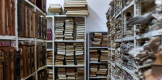 Dense archive storage room with metal shelves packed with bound volumes and checkered tile floor, illustrating systematic organization and categorization principles for directory structures.
