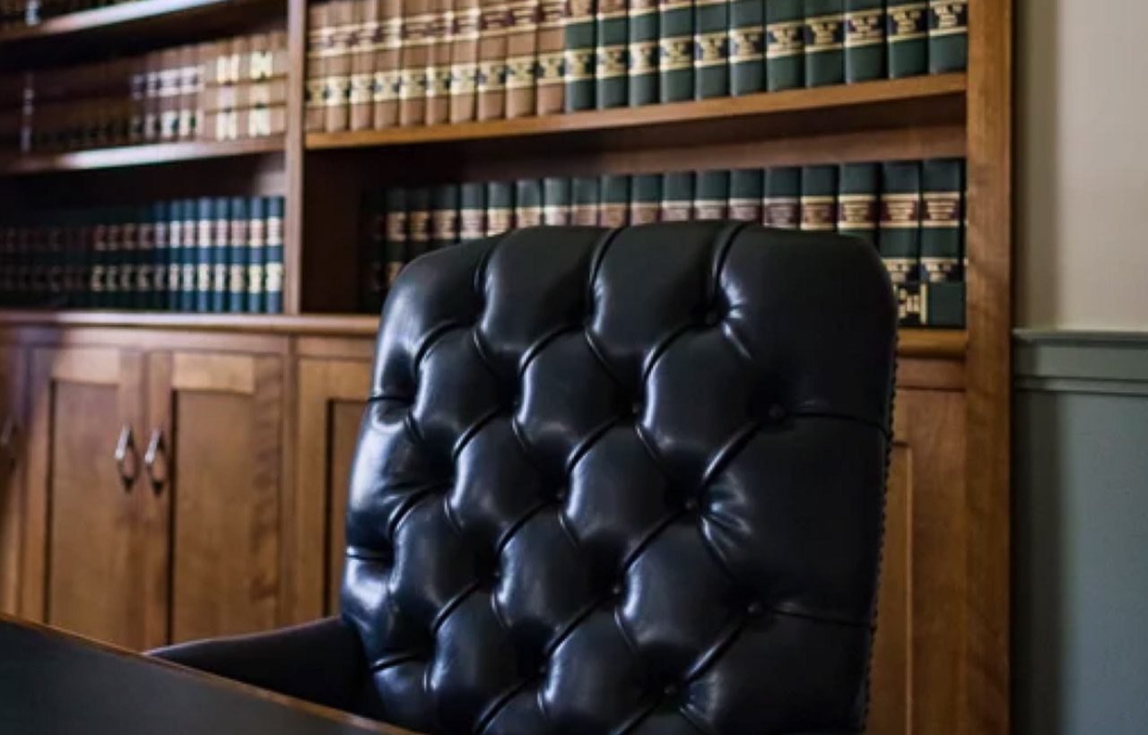 Black tufted leather executive chair sits before wooden bookcases filled with law books, representing the authority and organization of trusted online directories.