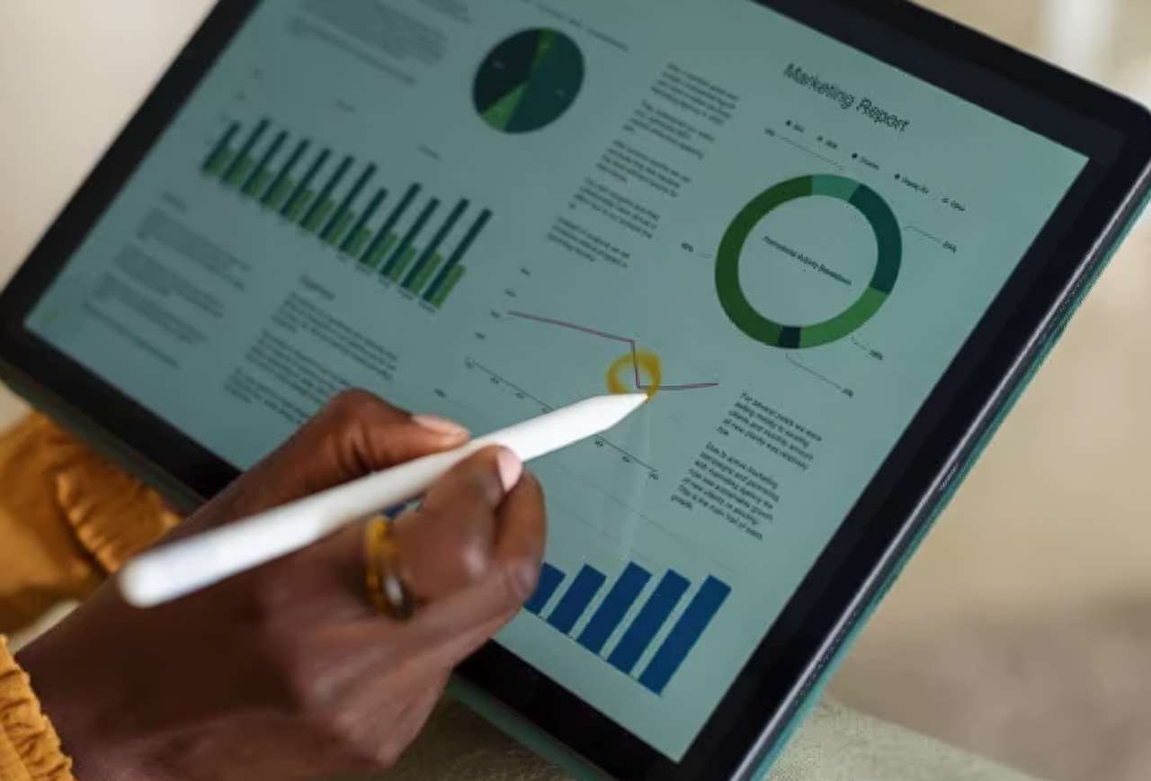Hand with stylus interacting with tablet displaying analytics dashboard featuring colorful charts and graphs, representing directory performance measurement tools.