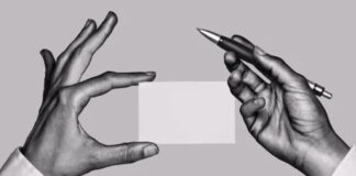 Two hands exchange a blank business card with a pen in a professional black and white photograph, representing traditional business marketing communication.