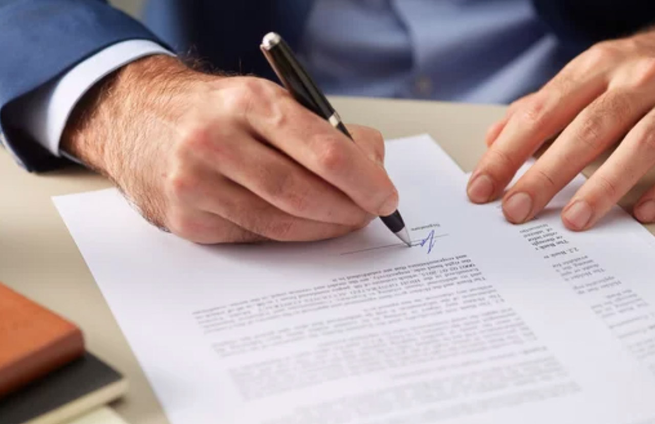 Close-up of business professional's hands signing a document with a pen, symbolizing the commitment required for maintaining quality business directory listings.