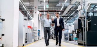 What Is a White Label Prop Firm? A Founder’s Guide to Launching Two businessmen walking through a modern manufacturing facility with industrial machinery, illustrating contemporary approaches to B2B advertising in technical industries.
