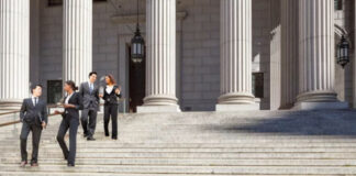 Business professionals meet on stone steps of a neoclassical columned building, illustrating the importance of strong foundational structure in SEO planning.