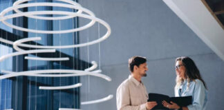What Is a Business Directory in the Age of AI Search Two business professionals review information on a tablet in a contemporary office with spiral sculpture, representing modern approaches to business directories and digital search.
