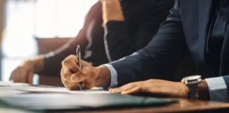 Future-Proof Your Business With Quality Directory Listings Two business professionals in suits review and sign documents at an office desk, representing the careful attention to detail required for maintaining accurate business directory listings.