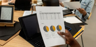Person holding a printed business report with pie charts and data tables over an office desk, representing analysis of Canadian provincial directory performance rankings.