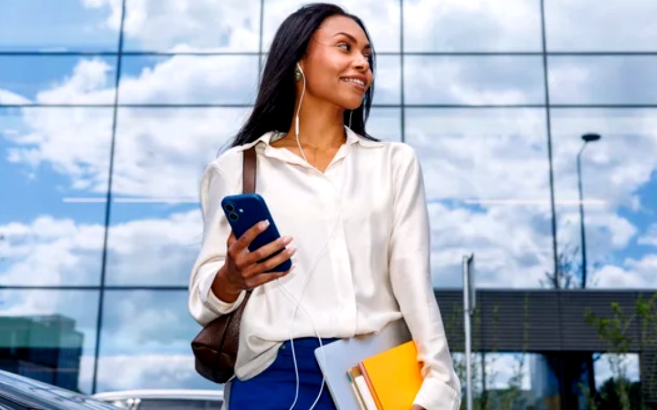 Business professional stands outside modern office building holding smartphone and notebooks, representing strategic preparation for Google's evolving search landscape.