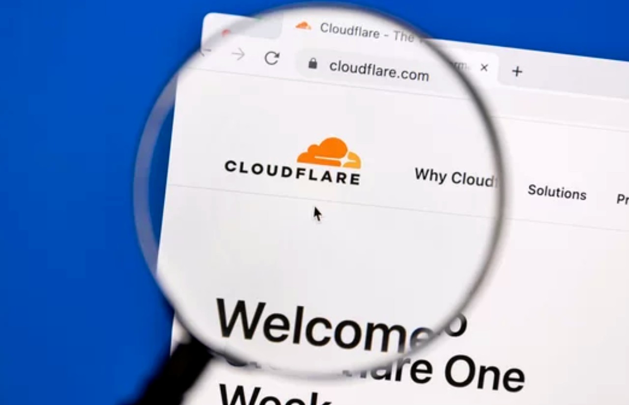 Magnifying glass examining Cloudflare website homepage on a computer screen, symbolizing the detailed technical analysis required for SEO optimization and site architecture review.